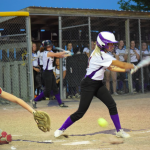 Softball player hitting ball with team in background