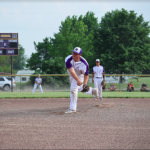 Boy pitching on mound with players in background