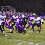 Football players on field with other team in the middle of a play